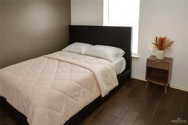 a large bed sitting in a bedroom next to a window with wooden floor