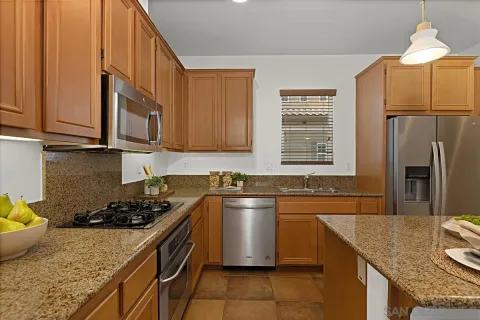 a kitchen with stainless steel appliances granite countertop a sink a stove and a refrigerator