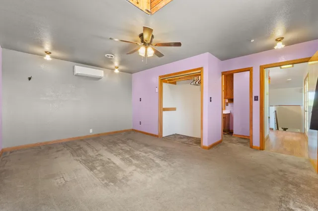 an empty room with chandelier fan and windows