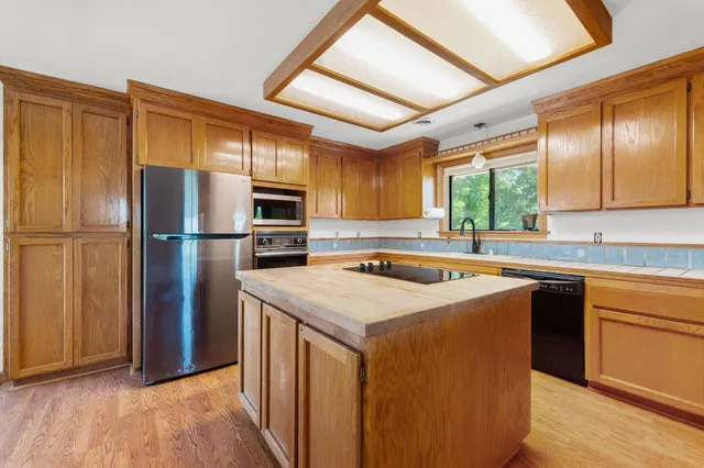 a kitchen with stainless steel appliances granite countertop a refrigerator a sink dishwasher a stove with wooden cabinets and floor