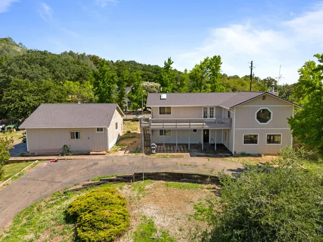 a view of a house with pool and trees in the background
