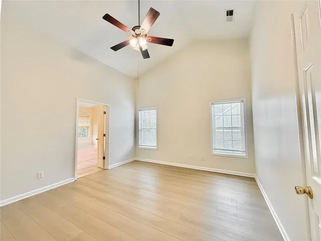 an empty room with wooden floor and windows