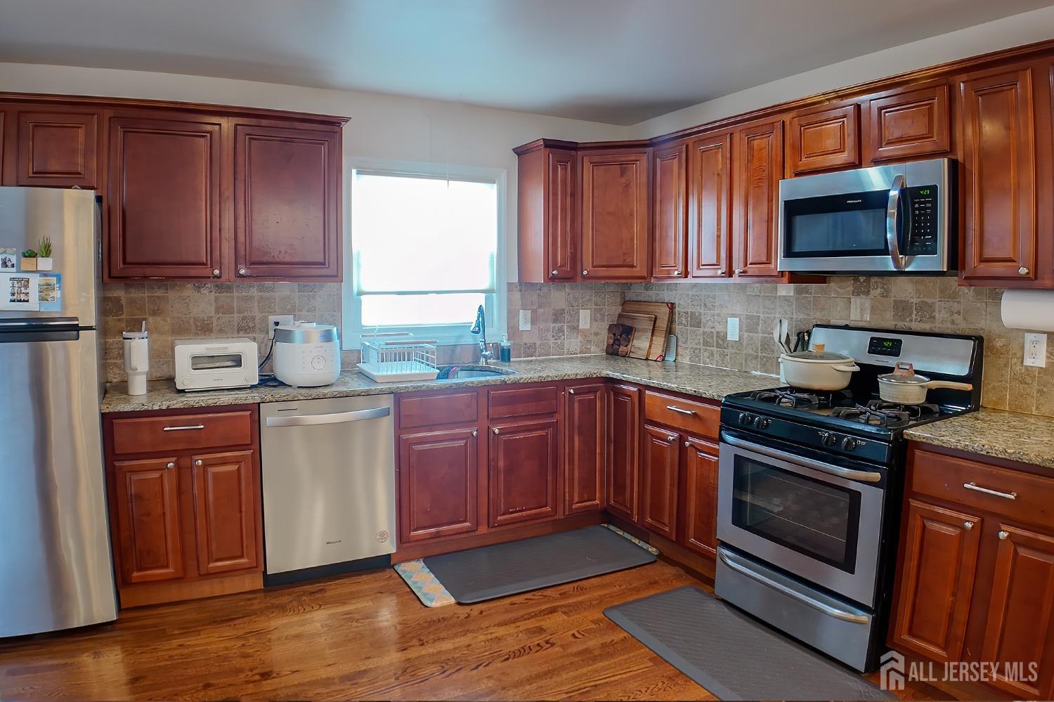 202 Jackson Avenue Edison, NJ 08837 - Photo 11 of 35 a kitchen with granite countertop wooden cabinets stainless steel appliances and a window