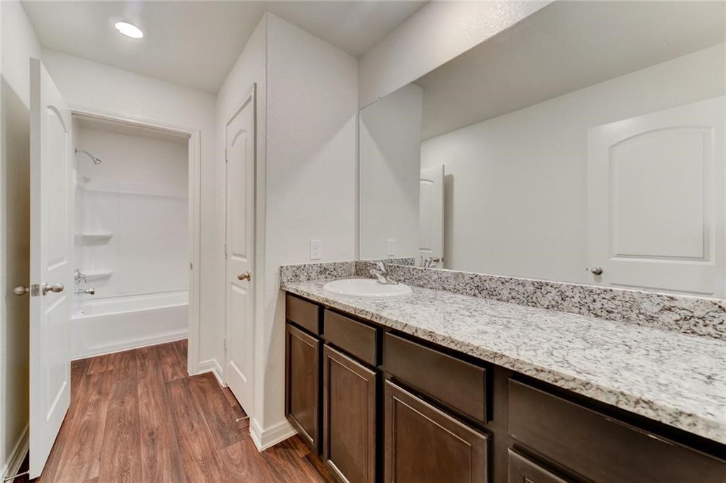 112 Dupont Pass Jarrell, TX 76537 - Photo 14 of 17 a bathroom with a granite countertop sink and a bathtub
