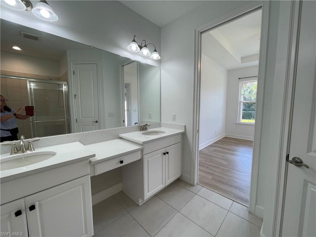 8217 Lucello Terrace West Naples, FL 34114 - Photo 18 of 41 a spacious bathroom with a granite countertop sink a mirror and a shower