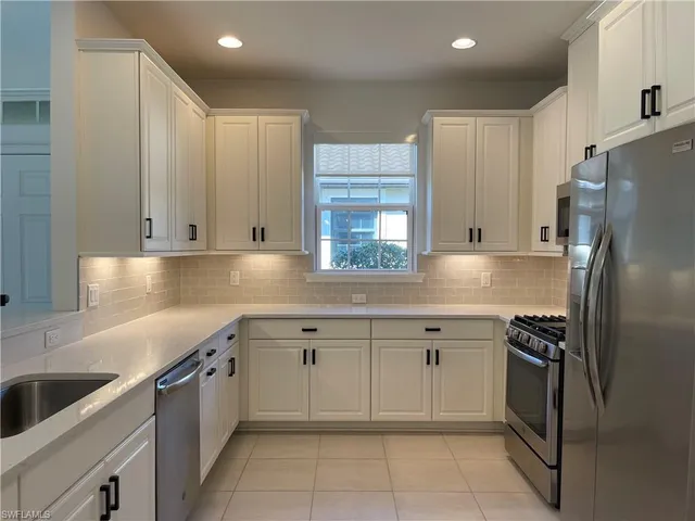 a kitchen with granite countertop a sink stove and refrigerator