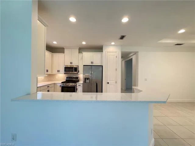 a large kitchen with stainless steel appliances a large counter top and a stove top oven