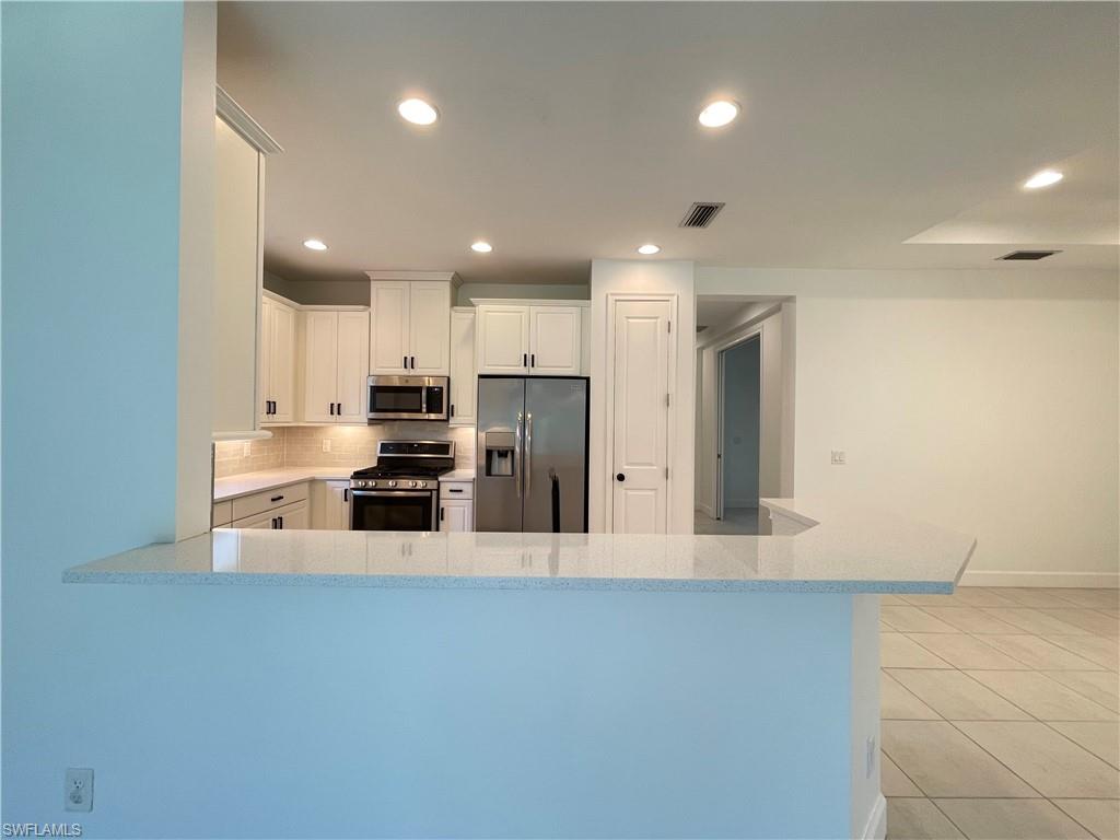 8217 Lucello Terrace West Naples, FL 34114 - Photo 7 of 41 a large kitchen with stainless steel appliances a large counter top and a stove top oven