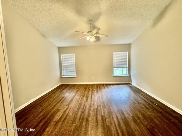 an empty room with wooden floor fan and window