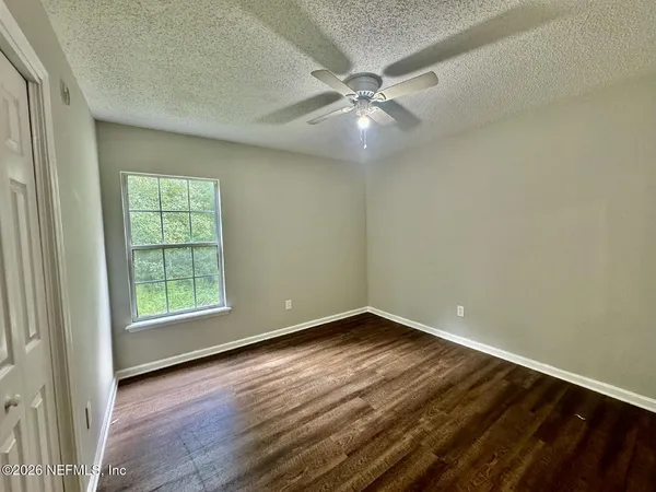 an empty room with wooden floor fan and windows