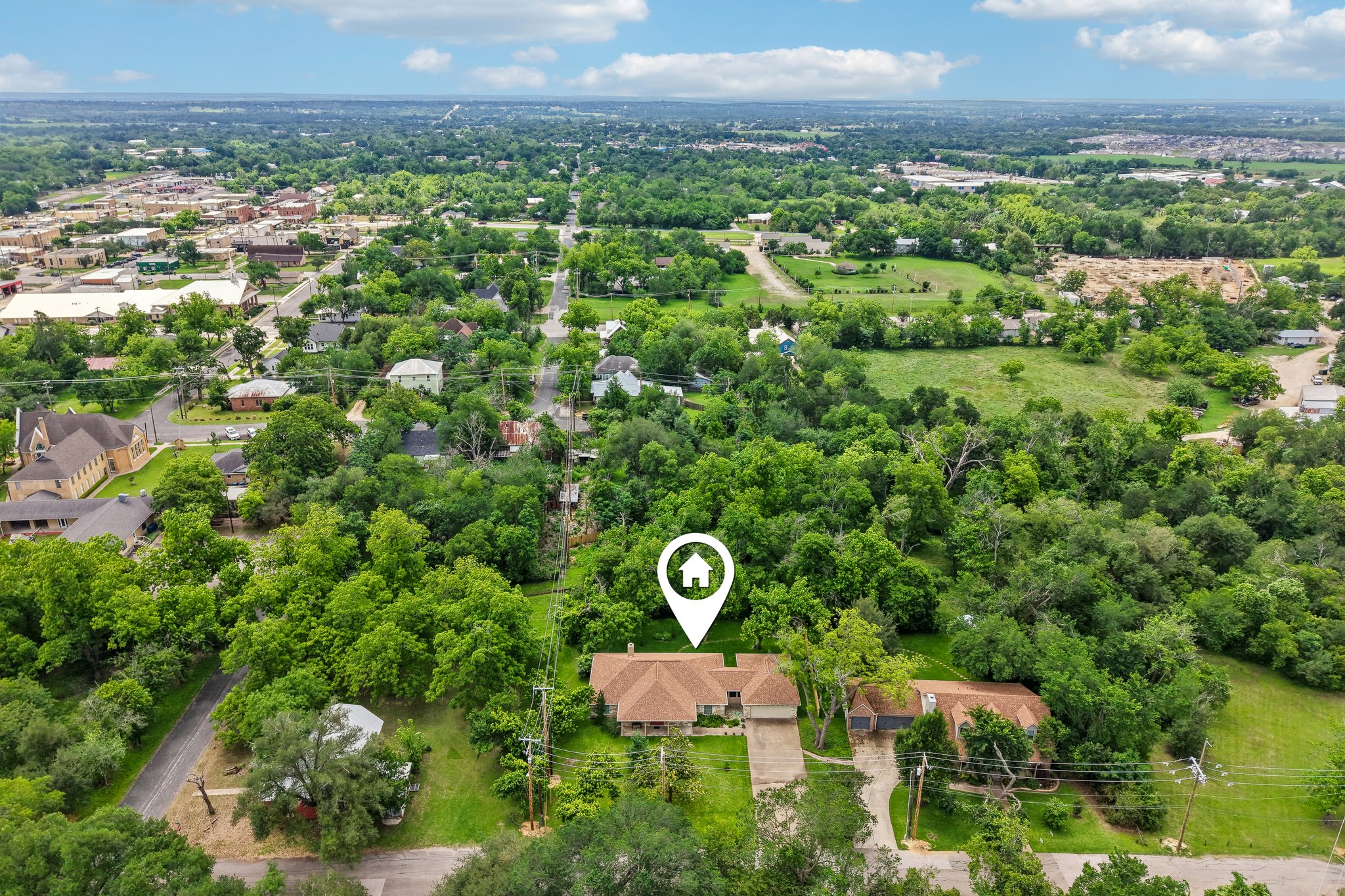 307 West 4th Street Elgin, TX 78621 - Photo 39 of 40 Aerial view showcasing a residential property with a brown-shingled roof and an attached garage