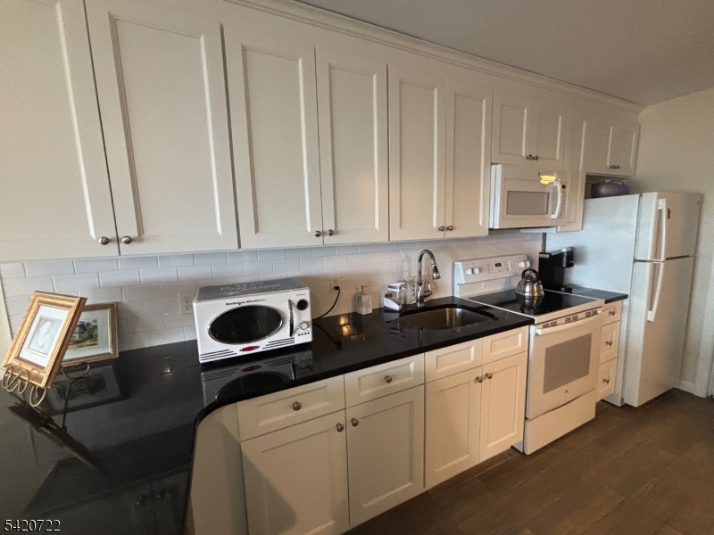 1935 Oceanfront, Unit 20 Seaside Heights, NJ 08751 - Photo 12 of 16 a kitchen with stainless steel appliances granite countertop white cabinets a sink and a refrigerator