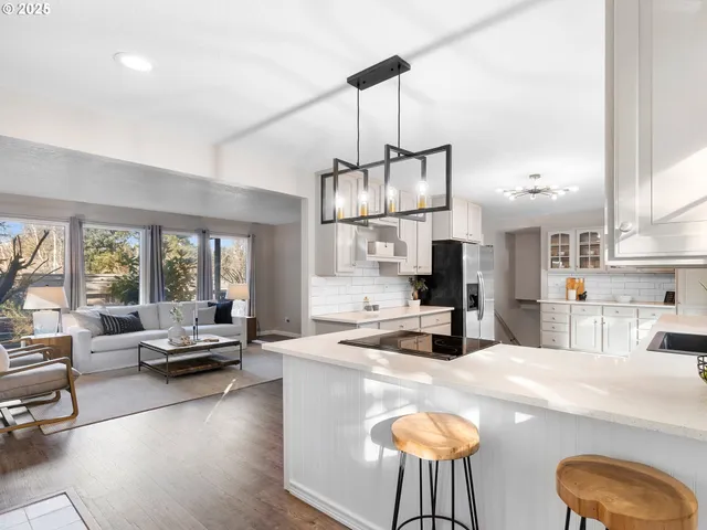 a kitchen with kitchen island a large counter space a sink appliances and a living room view