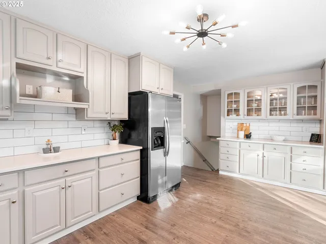 a kitchen with a refrigerator a sink dishwasher a stove and white cabinets with wooden floor