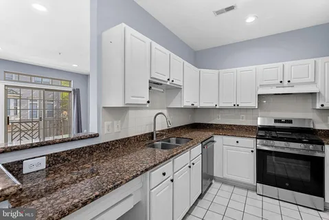a kitchen with granite countertop a stove sink and refrigerator