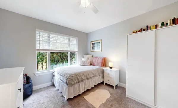 a bedroom with a bed and a window with cabinet
