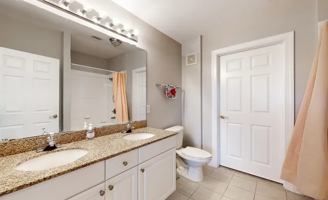 a bathroom with a granite countertop sink a toilet and a mirror