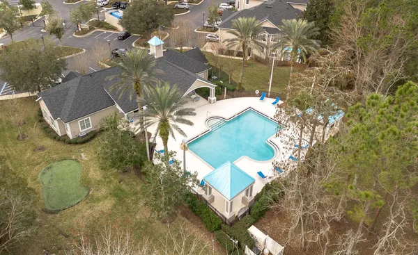 an aerial view of a house with swimming pool and large trees