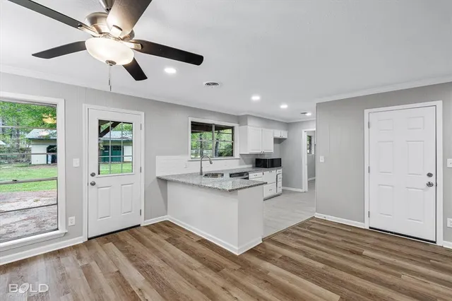 a view of an empty room with wooden floor fireplace and a window