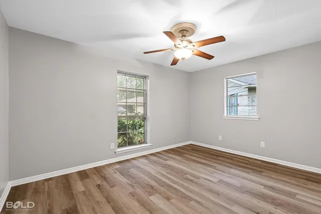 an empty room with a window and a ceiling fan