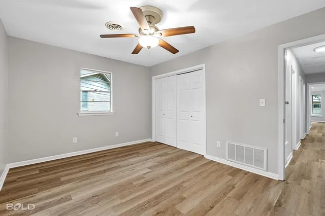 a view of empty room with wooden floor and fan