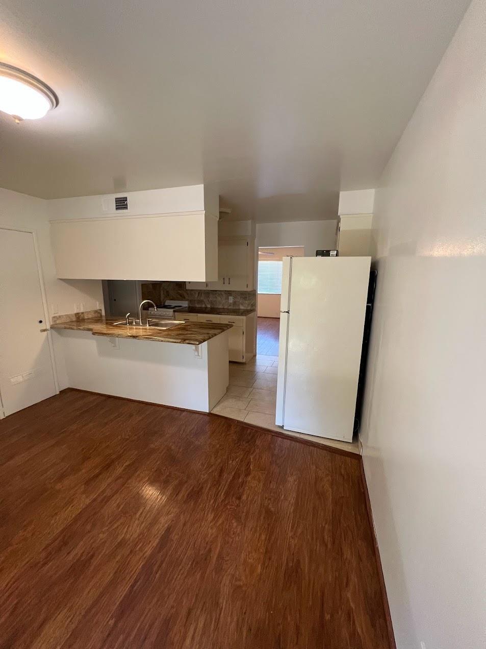 1205 F Street Reedley, CA 93654 - Photo 7 of 33 a kitchen with wooden floors and white appliances