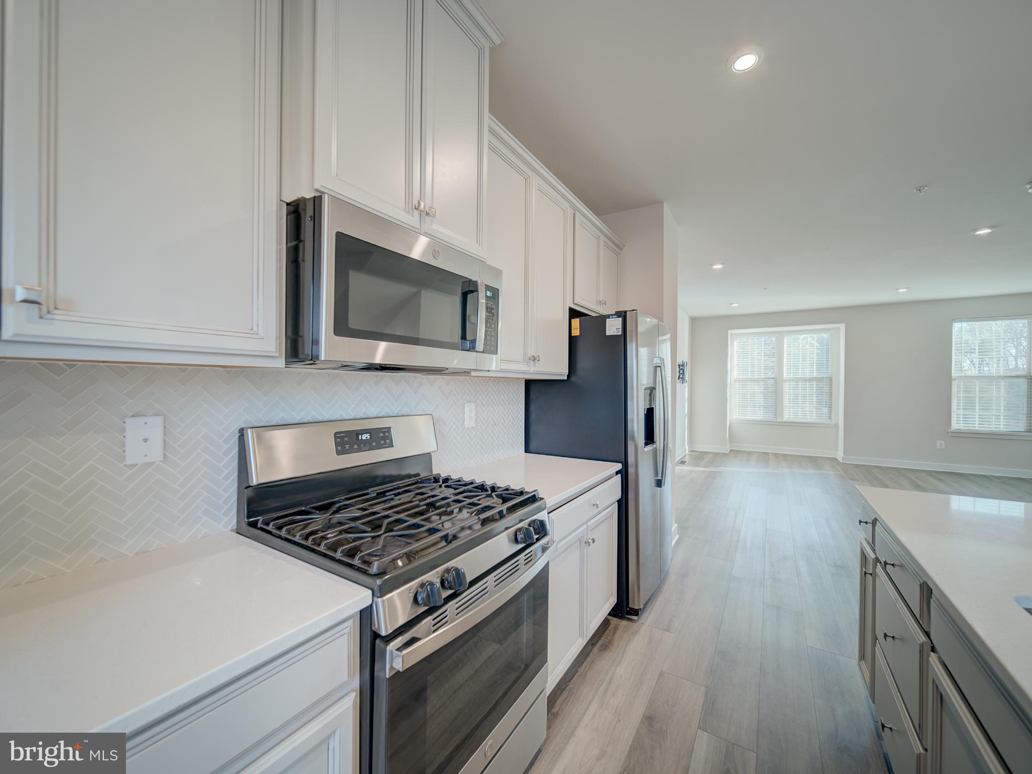 9502 Autumn Berry Place Montgomery Village, MD 20886 - Photo 16 of 36 a kitchen with granite countertop a stove top oven a sink dishwasher and white cabinets with wooden floor