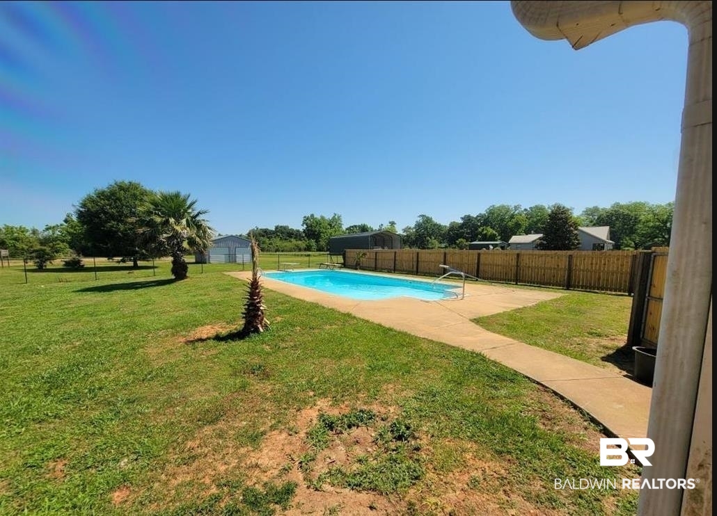 16311 Old Brady Road Bay Minette, AL 36507 - Photo 15 of 38 Expansive backyard featuring a blue-tiled swimming pool with integrated steps, a concrete pool deck, and a privacy fence