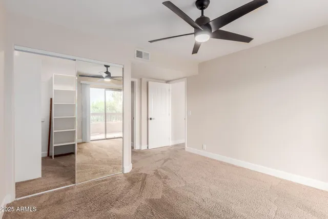 an empty room with chandelier fan and windows