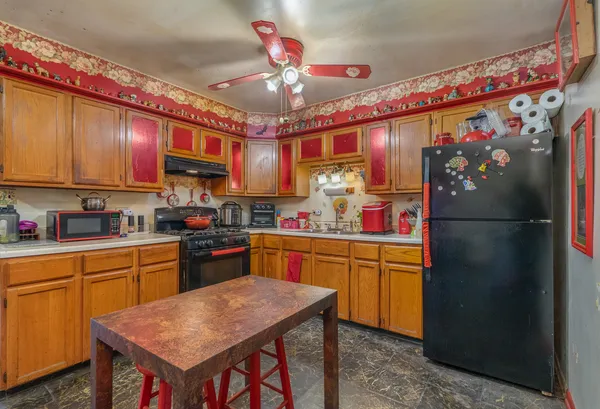 a kitchen with stainless steel appliances granite countertop a refrigerator a sink dishwasher a stove and a dining table with wooden floor