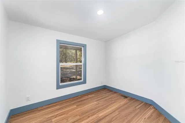 a view of an empty room with window and wooden floor