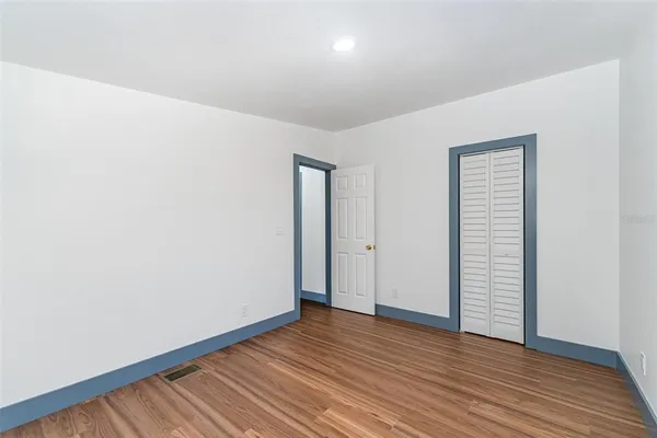 a view of an empty room with wooden floor and closet