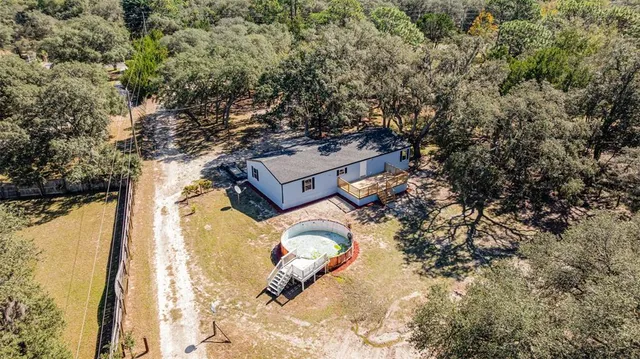 an aerial view of a house with swimming pool and large trees
