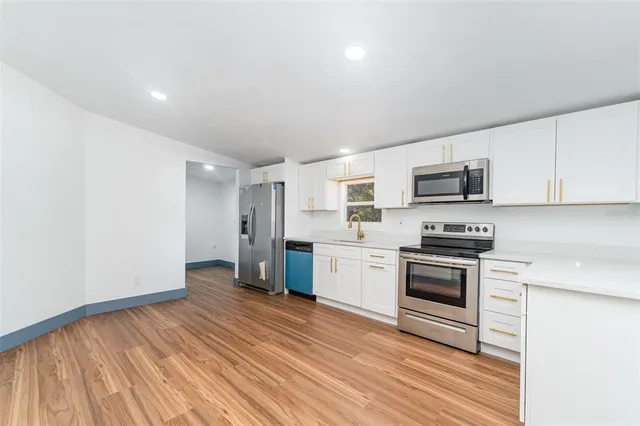 a kitchen with stainless steel appliances a stove top oven a sink dishwasher and a refrigerator