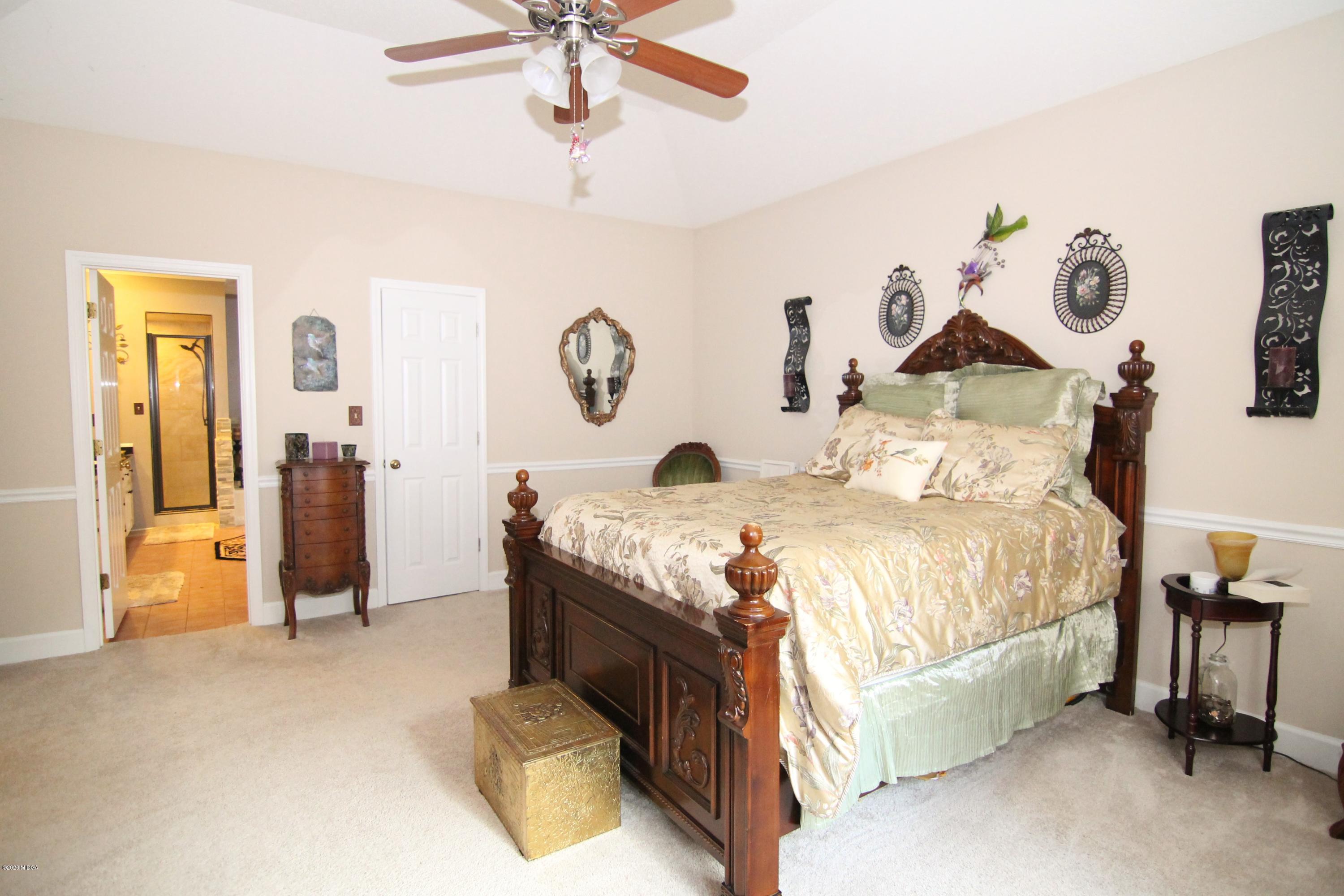 205 Cedar Ridge Drive Perry, GA 31069 - Photo 14 of 39 a spacious bedroom with a bed and a chandelier
