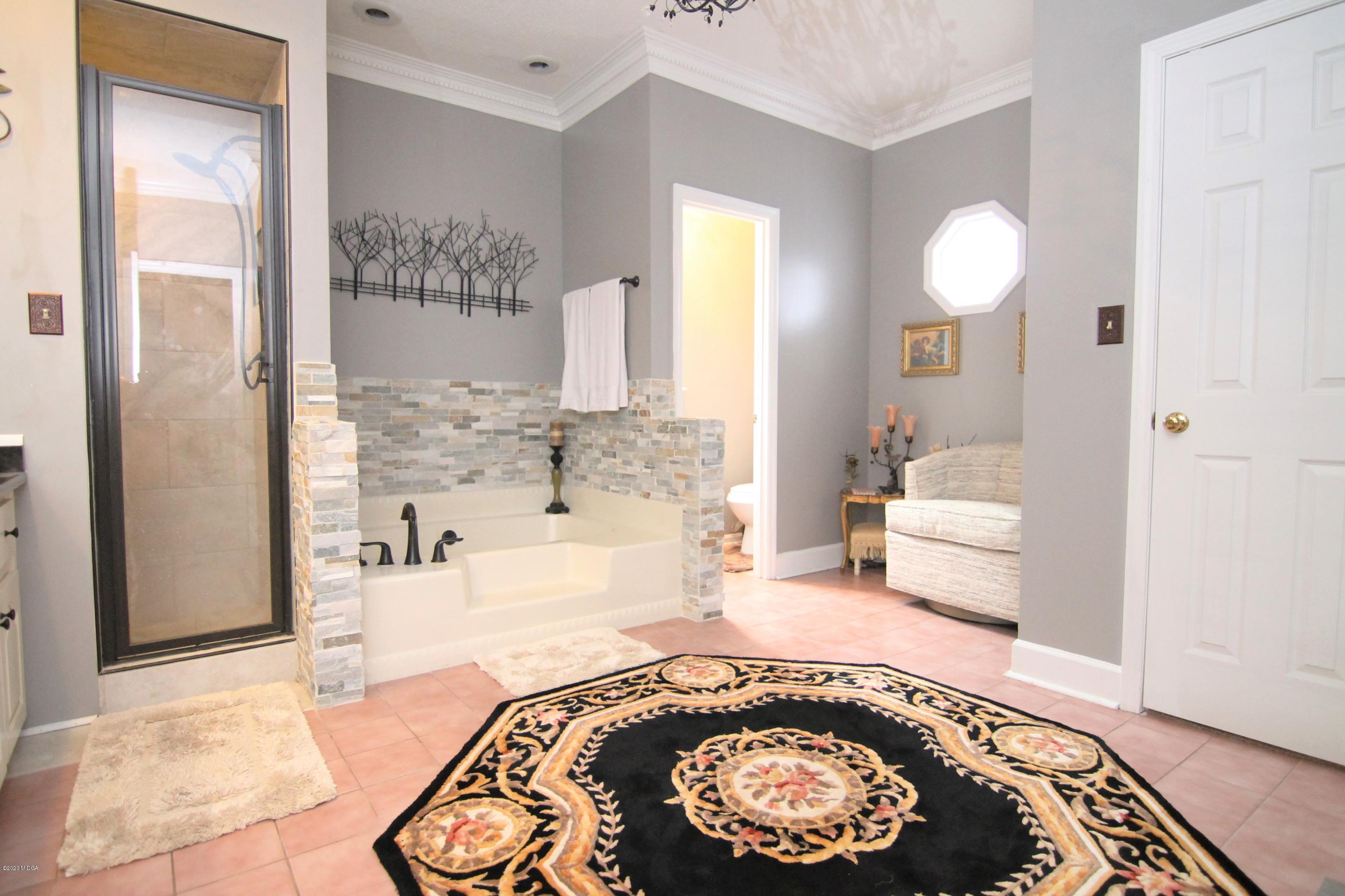 205 Cedar Ridge Drive Perry, GA 31069 - Photo 16 of 39 a spacious bedroom with a bed and a chandelier