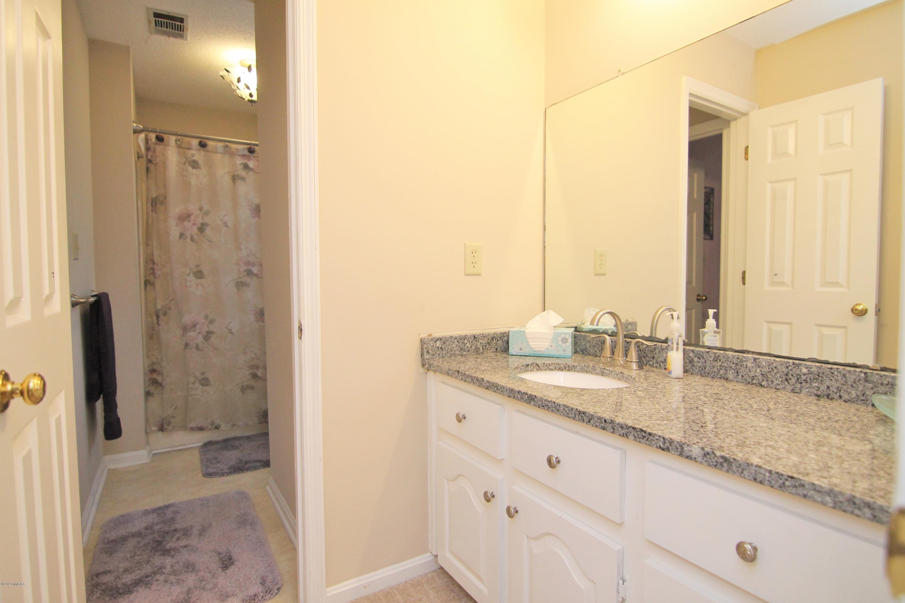 205 Cedar Ridge Drive Perry, GA 31069 - Photo 28 of 39 a bathroom with a granite countertop sink a mirror and a shower