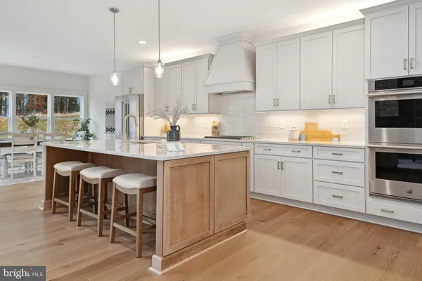 a kitchen with stainless steel appliances granite countertop a table chairs sink and cabinets
