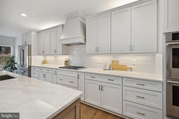 a large white kitchen with lots of counter top space a sink appliances and cabinets