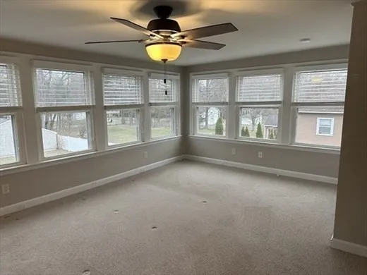 an empty room with window and chandelier fan