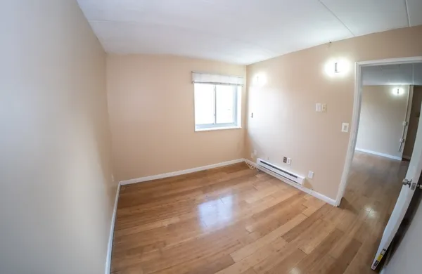 an empty room with wooden floor and mirror
