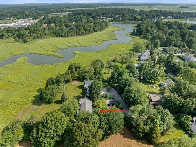 an aerial view of a house with a yard and trees all around