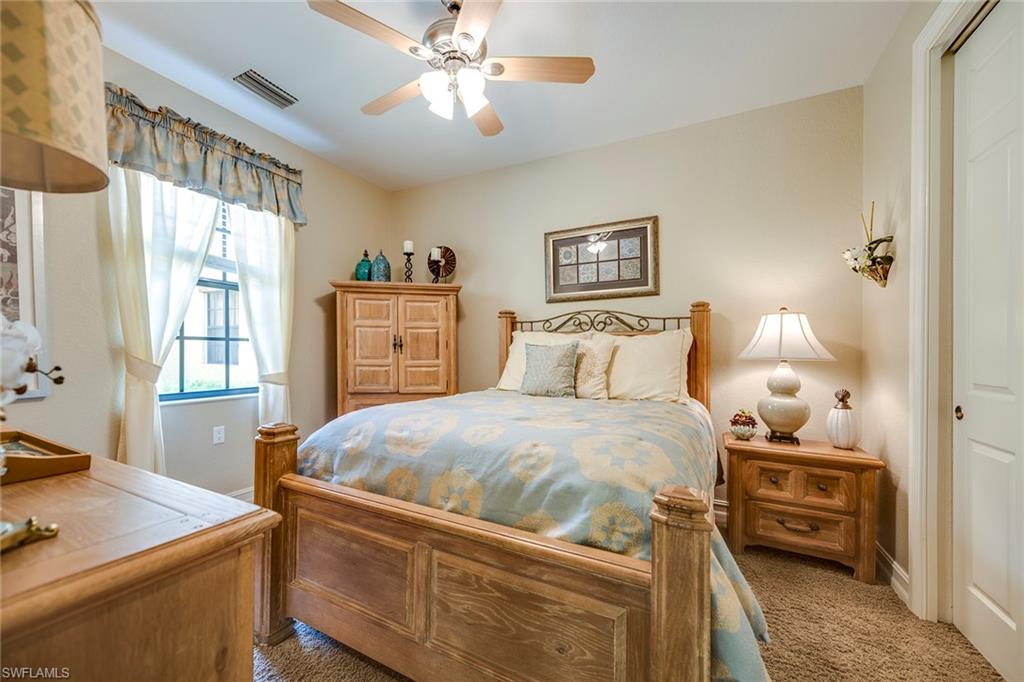 9161 Chula Vista Street, Unit 1352 Naples, FL 34113 - Photo 16 of 23 a bedroom with a bed and a chandelier