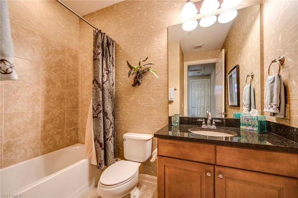 9161 Chula Vista Street, Unit 1352 Naples, FL 34113 - Photo 21 of 23 a bathroom with a sink a toilet a mirror a bathtub and shower