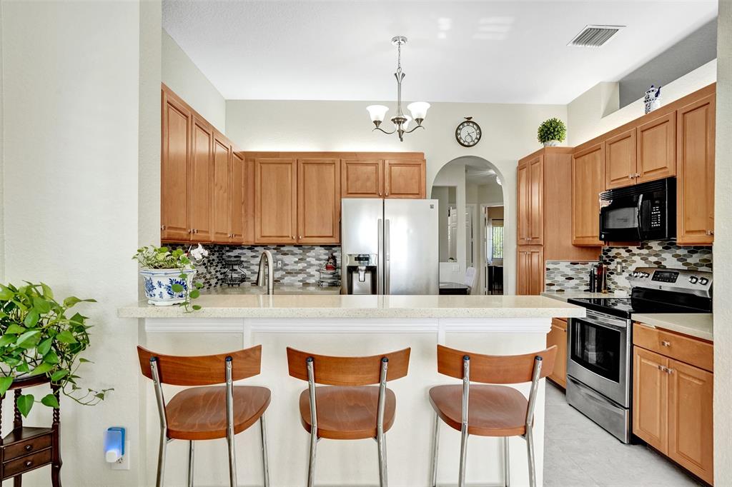 7967 Exeter Boulevard East, Unit 203 Tamarac, FL 33321 - Photo 11 of 42 a kitchen with stainless steel appliances kitchen island granite countertop a dining table chairs and granite counter tops