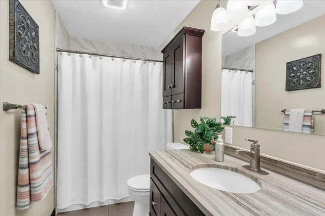 a bathroom with a granite countertop sink a toilet and a mirror