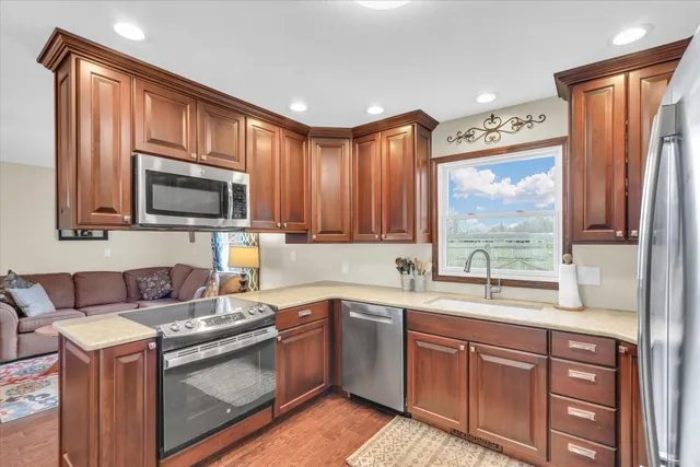 a kitchen with granite countertop wooden cabinets stainless steel appliances a window and a sink
