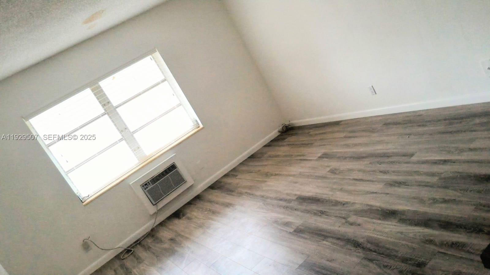 1755 Northeast 116th Road, Unit 15 North Miami, FL 33181 - Photo 2 of 9 an empty room with wooden floor and windows