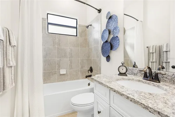 a bathroom with a granite countertop sink a toilet and a bathtub