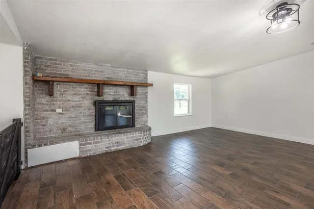 an empty room with wooden floor fireplace and windows